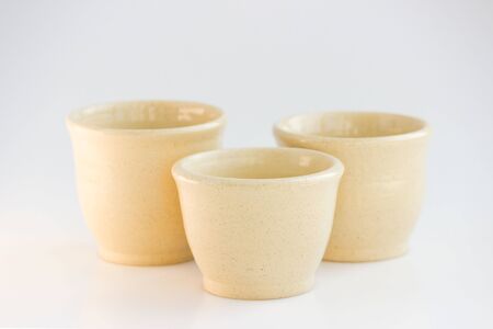 Three beige tea bowls. handwork. cups of different sizes are made on a pottery wheel.の写真素材