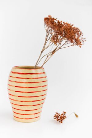 beige clay plate on a white background. minimalism style. handwork and dried flower. vertical photoの写真素材