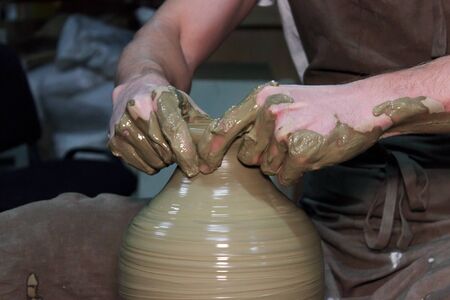 Experienced potter makes a large vase on a potter's wheel.の写真素材