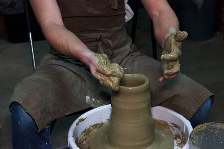 experienced potter makes a large vase on a potter's wheel. clay product. hands of a potter. reportage shootingの写真素材