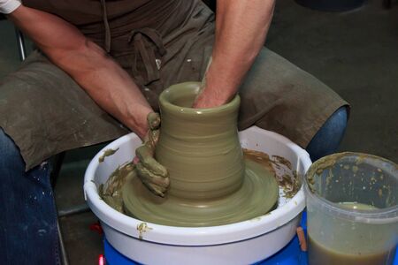 experienced potter makes a large vase on a potter's wheel. clay product. hands of a potter. reportage shootingの写真素材