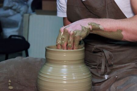 experienced potter makes a large vase on a potter's wheel. clay product. hands of a potter. reportage shootingの写真素材