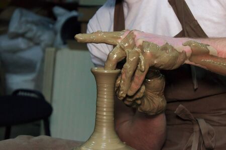 experienced potter makes a large vase on a potter's wheel. twisting a narrow neck. clay productの写真素材