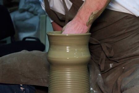 experienced potter makes a large vase on a potter's wheel. clay product. hands of a potter. reportage shootingの写真素材
