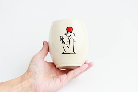 Clay vase with the ancient Egyptian hieroglyph God Ra with ankh in hand on a whiteの写真素材
