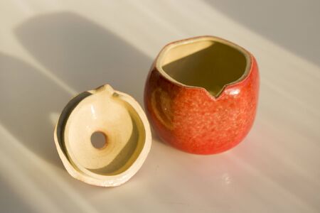 red ceramic pomegranate. vase, casket, decor, art object for the interior. pomegranate - a symbol of health, fertility and family. with coverの写真素材
