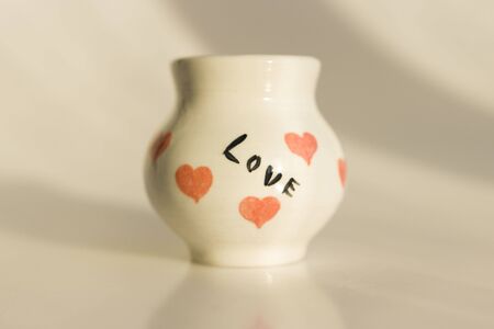 small white pot with hearts and the inscription Love. ceramic product. author's work.の写真素材