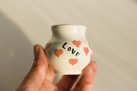 small white pot with hearts and the inscription Love. ceramic product. author's work.の写真素材