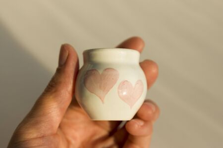 small white pot with two hearts. concept love. ceramic product. author's workの写真素材