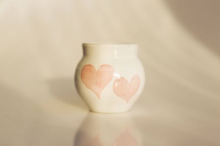 small white pot with two hearts. concept love. ceramic product. author's workの写真素材