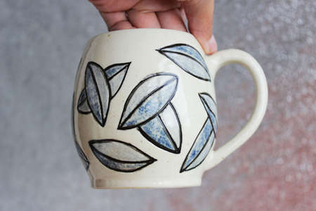 handmade ceramic cup with leaves. clay covered with engob, glaze and passed two firing.の写真素材