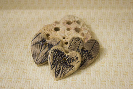 ceramic hearts made of clay with imprints of plants lie on a limestone stone on a beige background. trypophobia. handmadeの写真素材