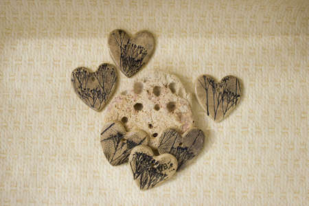 ceramic hearts made of clay with imprints of plants lie on a limestone stone on a beige background. trypophobia. handmade.の写真素材