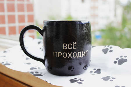 black cup with an inscription in Russian: Everything passes. the words of King Solomon from the ancient parable about the ring. All will passの写真素材
