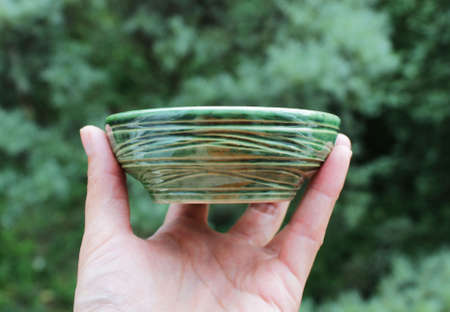 handmade green ceramic plate. made on a potter's wheel, covered with spectacular glaze, passed two firing.の写真素材