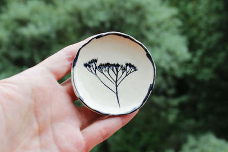 small ceramic plate with a plant print. made from a layer of clay. handmade.の写真素材