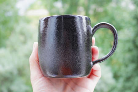 black mug made of clay. decor - covering with black engobe and transparent glaze. two firing. made on a potter's wheel. handmade.の写真素材