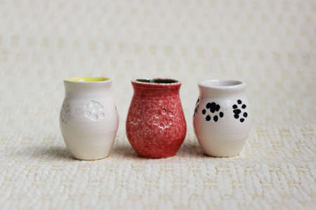 three small pots with cat paws on a beige background. handmade. made on a potter's wheel.の写真素材