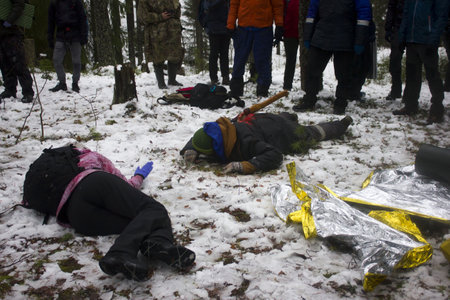 Ambulance drills in the winter forest. Several allegedly drunk people lie with knives and axes in their backs and resist helping. Reportage shooting from the sceneの写真素材