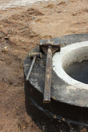 two homemade construction sledgehammers lie on the storm drain. Repair and widening of the road at the exit from Gatchina, Russia.の写真素材