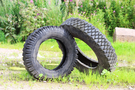two tires from the car lie on the green grass. The concept of pollution of the environment and industrial industry that attacks natureの写真素材