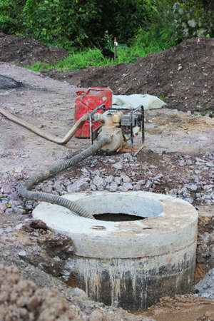 concrete ring from storm drain and pump that pumps out rainwater on road. road repair and widening, reportage vertical photoの写真素材