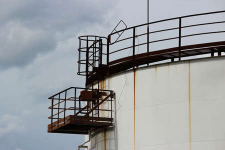 huge industrial tank with a metal ladder against the blue skyの写真素材