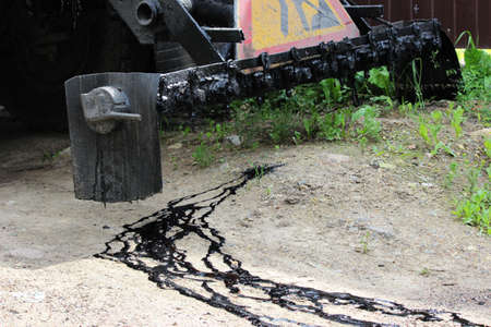 road repair car bitumen truck or asphalt distributor with black resin flowing by gravity. for the restoration of auto-concrete road surfacesの写真素材