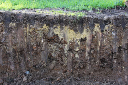 soil layers visible after excavation with an excavator with bucket marks. repair and widening of the road, extraction of peat soil before repairの写真素材