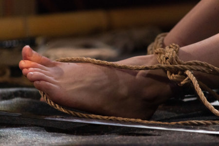 tied legs of a girl on stage during a performance at a bdsm festival. reportage shooting.の写真素材