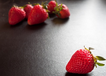 red fresh delicious strawberry on black with back lightの写真素材