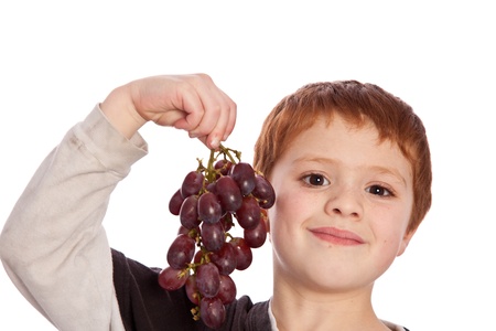 young boy isolated on a white background showing fresh picked grapesの写真素材