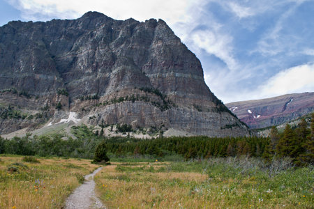 hiking trail in to the mountains with a couple in the distance and beautiful layes on the rocks