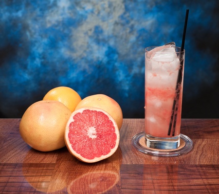 fresh grapefruits on a bar one of them sliced and a tall glass filled with juice and vodkaの写真素材