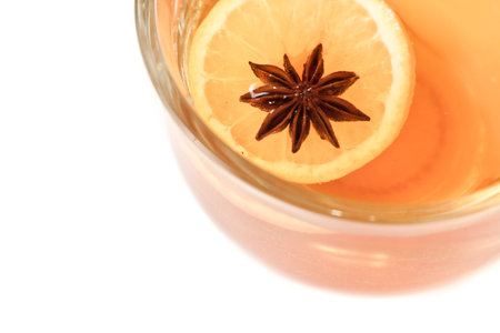 close up of an Anise star floating with an orange star in a hot cup of tea
