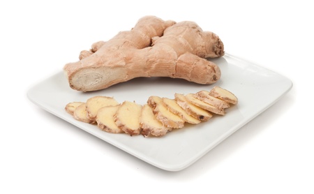 fresh ginger sliced on a white plate isolated on a white backgroundの写真素材