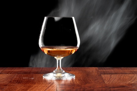 Brandy snifter on a bar top isolated on a black backgroundの写真素材
