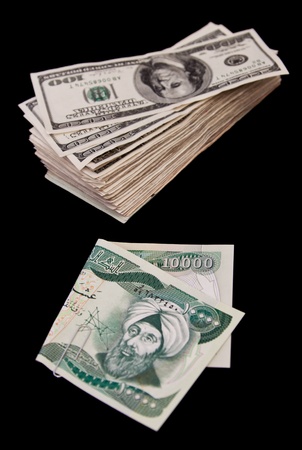 ten thousand Iraqui dinar bill and a bunch of hundred dollar bills isolated on a black backgroundの写真素材