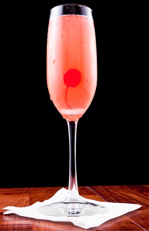 pink champagne cocktail with a cherry isolated on a black backgroundの写真素材