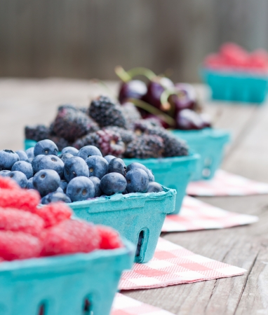 fresh berries for sale placed on a table in a row, blueberries in focus with shallow depth of fieldの写真素材