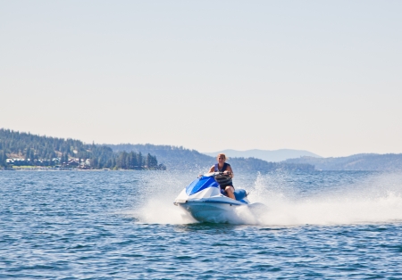 Beautiful woman out on the lake riding a wave runner on bright sunny dayの写真素材