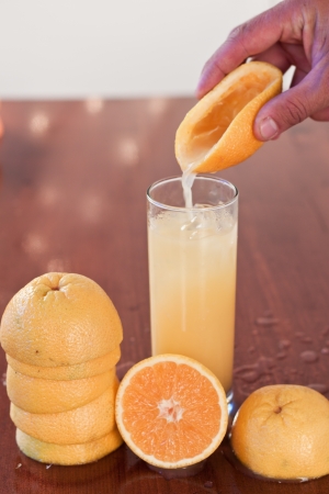 Fresh pressed orange juice into a glass on a wooden bar topの写真素材