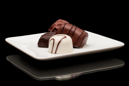 bite size chocolates on a white plate decorated with dark chocolate swirls