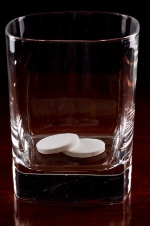 pills in a glass over a dark wooden tableの写真素材