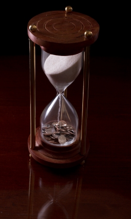 hour glass on a dark background with american money in itの写真素材