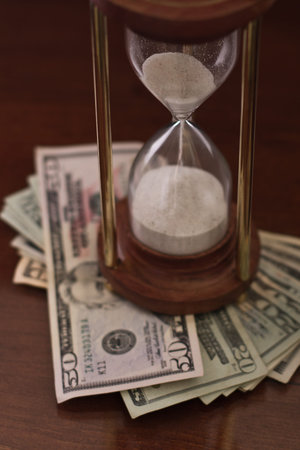 concept of an hour glass with time passing over money