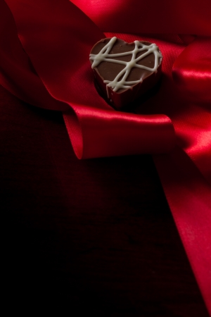 heart shaped chocolate hazelnut with cream and toffee on a red silk fading in to blackの写真素材