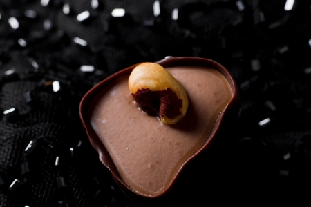hand crafted chocolate dessert cups with praline filling on a dark silk backgroundの写真素材