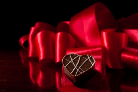 heart shaped chocolate hazelnut with cream and toffee on a red silk fading in to blackの写真素材