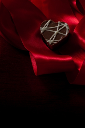 heart shaped chocolate hazelnut with cream and toffee on a red silk fading in to blackの写真素材